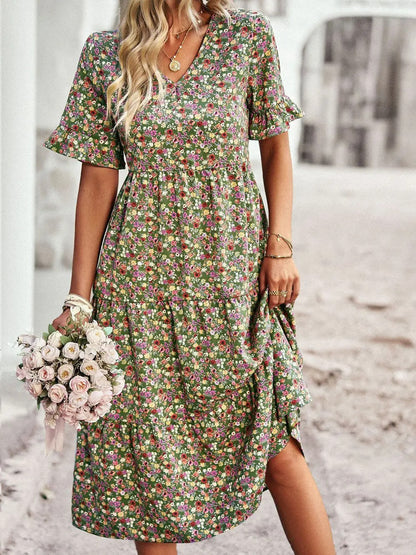 "Zomerjurk met bloemenpatroon en V-hals in abrikoos; elegante, casual damesjurk voor een stijlvolle zomerlook."